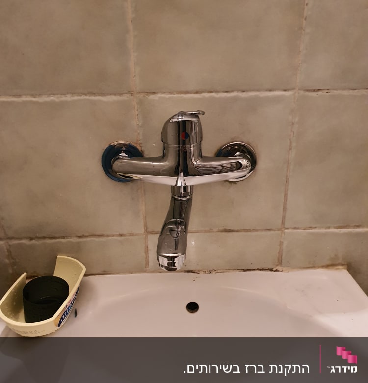 ברז כרום מותקן על קיר מעל כיור לבן